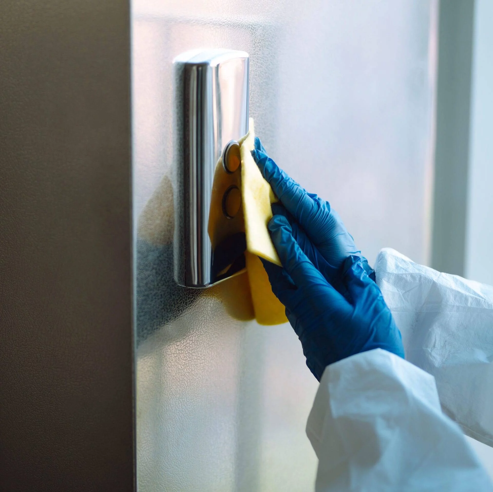 Cleaning and disinfection of the elevator to prevent COVID-19. Worker wearing protective suit sprays